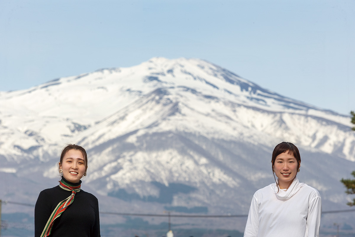 遊佐町から見える鳥海山を背景に。（写真右から）Oriori代表のかん奈さんとプランナーの優美さん