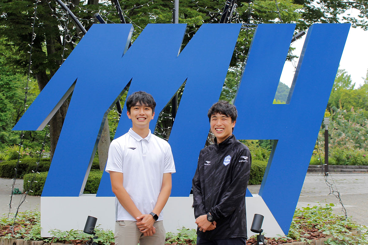 公園内に設置されたイニシャルモニュメントの前で。荒井薫さん(左)と原田祥平さん(右)