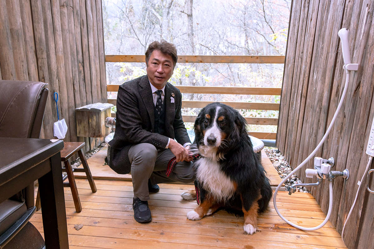 犬専用の露天風呂「弁財天」を案内してくれる岡崎さんと看板犬のほたるちゃん