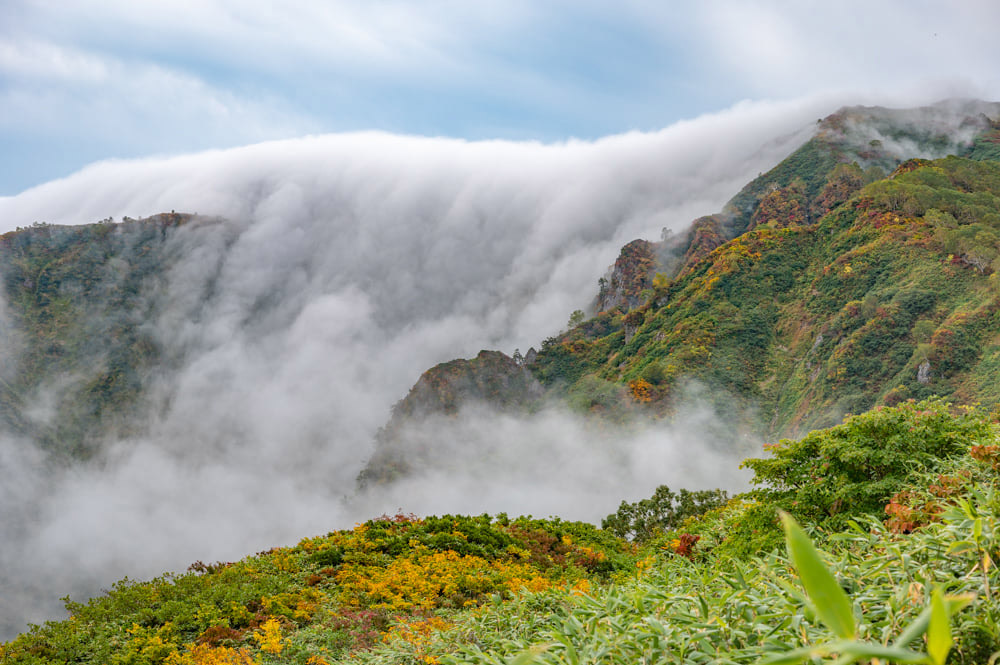 谷に溜まった雲が峰々を乗り越え滝雲となる