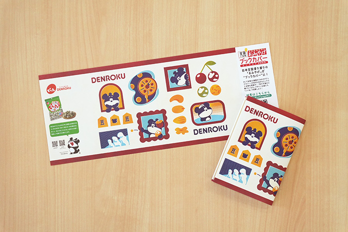 『全国ご当地おみやげブックカバーコンテスト2025』でグランプリを受賞したでん六。さくらんぼや将棋、樹氷など、山形の魅力を詰め込んだ郷土愛あふれるデザインが話題に（写真提供：でん六）